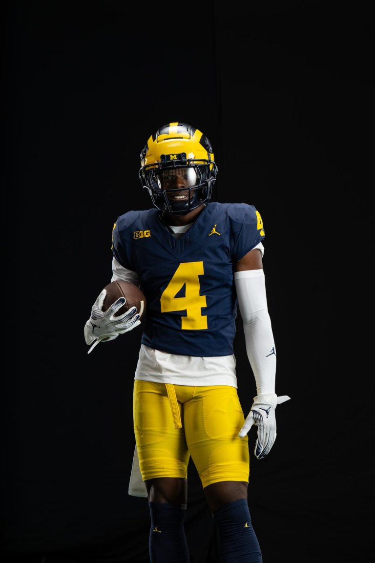 Andrew Marsh Poses for the camera, football in his hand and wearing a University of Michigan uniform